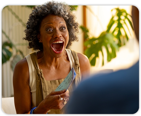 Close-up image of a woman holding flight tickets with a surprised face
